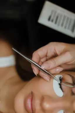 Lash extensions being applied with tweezers, close-up