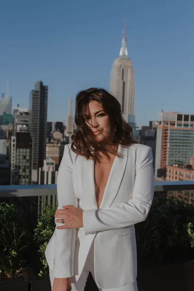 Whitney, founder of Whitney in the City, in a white suit on a Manhattan rooftop